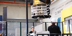 Engineers adjusting satellite on to UTS MAST